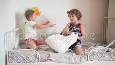 哥哥和姐姐在卧室的床上用枕头安排打架。 那个淘气的小女孩打败了